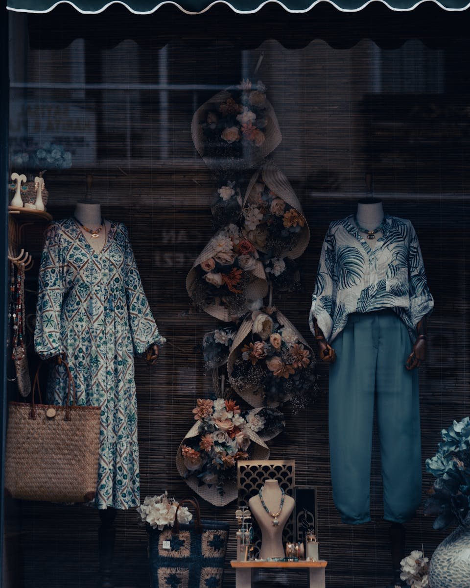Elegant storefront display featuring mannequins adorned with stylish outfits and floral arrangements.